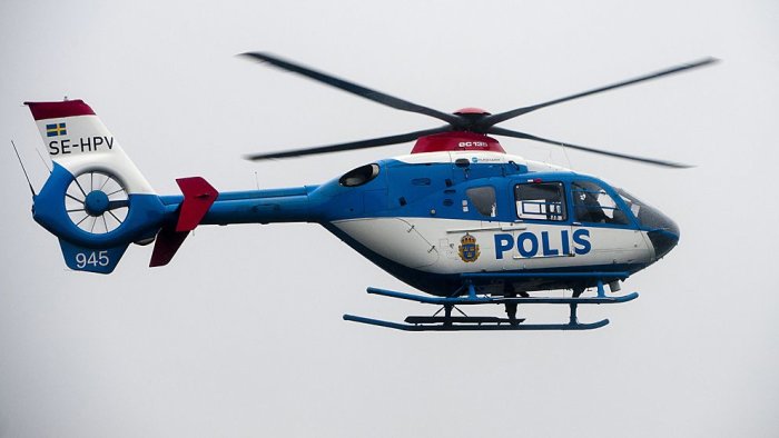 Blå och vit polis-helikopter i flykt med snurrande rotorblad och texten POLIS.