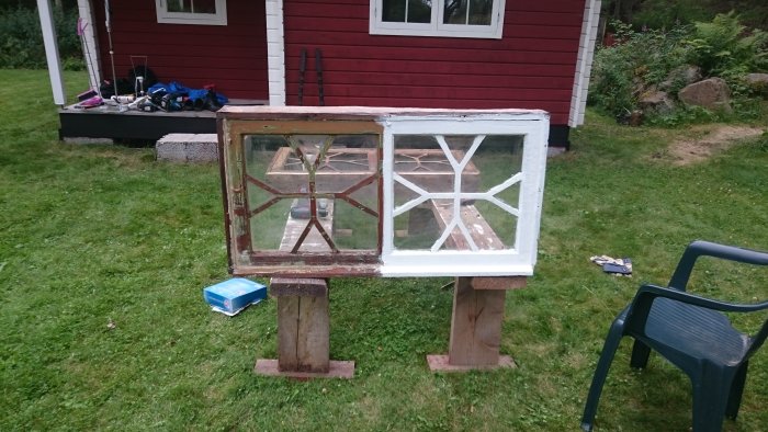 Renoverade dubbla fönster med linoljefärg på trästöttor framför ett rött hus, arbetsmaterial syns i bakgrunden.