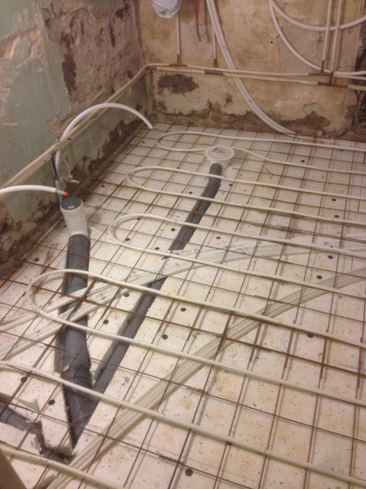 Armeringsnät och golvvärmerör inför gjutning av badrumsgolv under renovering.
