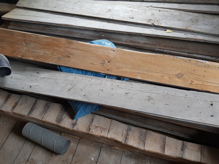 Gammalt och nytt golvvirke i en hög med synligt damm och spån.
