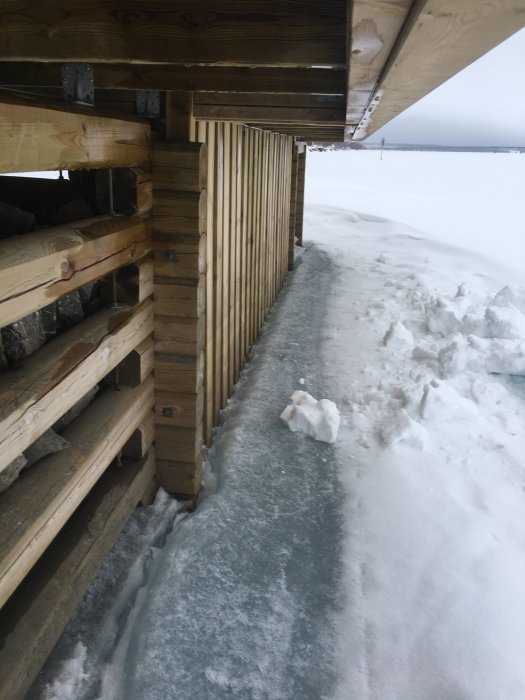 Vågskydd byggt av trä under en brygga som täcker isbelagda ytan intill vattnet på vintern.