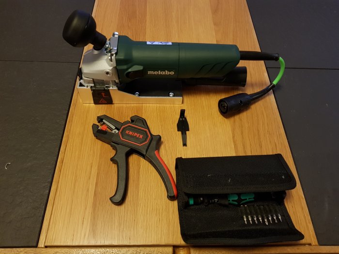 Verktyg för kontakt med kablar inklusive en Metabo-verktygsmaskin, Knipex-tång och bitsats på ett bord.