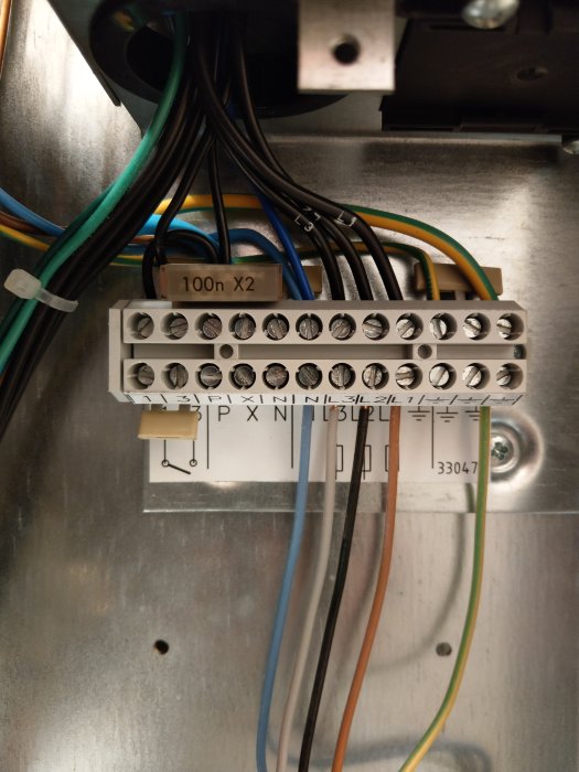 Översikt av elpannans invändiga elektriska anslutningar med en störskyddskondensator och flera kablar.