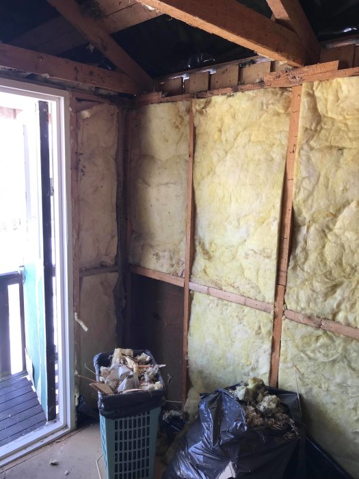 Renoveringsprojekt med exponerade väggstolpar och isolering, skadad isolering av möss i hörnet.