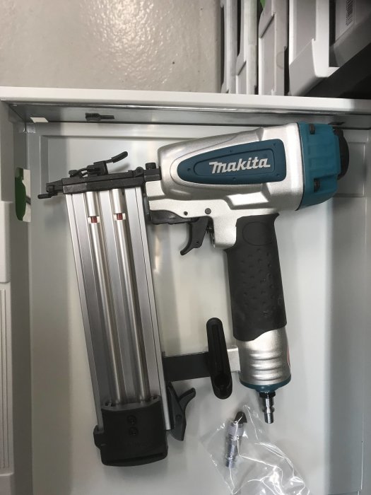 Ny Makita dyckertpistol upphängd på en vägg med tomma förpackningar undertill.