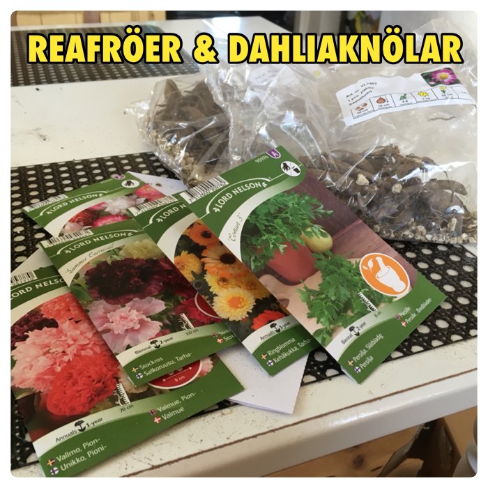 Flera fröpåsar och dahliaknölar på ett köksbord med texten "REAFRÖER & DAHLIAKNÖLAR" ovanpå.