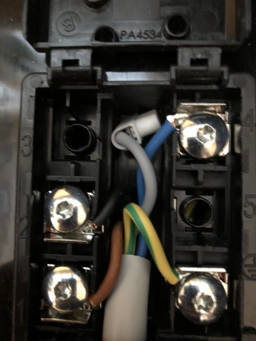 Eluttag med osäker grå isolerad kabel, och anslutna blå, brun och gul/grön kablar.