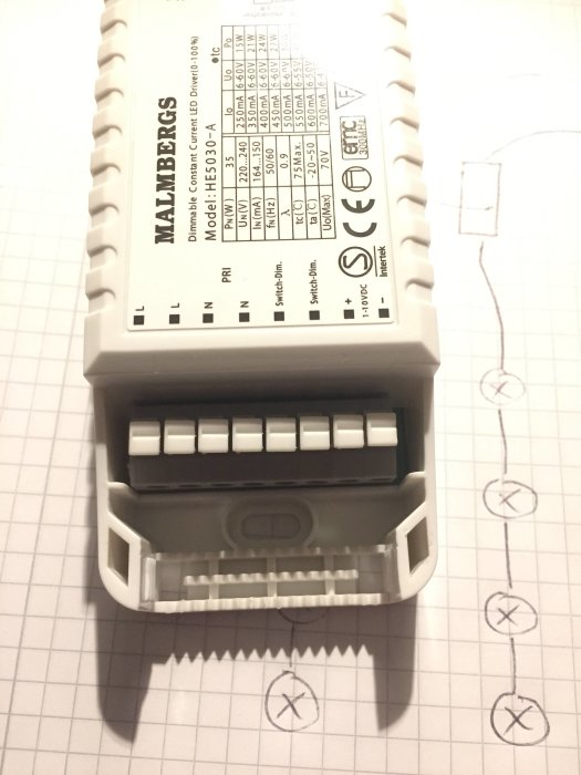 En eldrivdon med etikett och ledningar ritade på millimeterpapper som visar kopplingsschema.