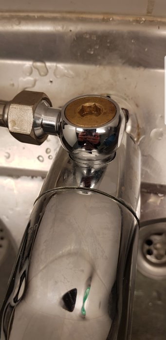 Närbild av en köksblandare med en ansluten vattenledning och en synlig sexkantig plugg.