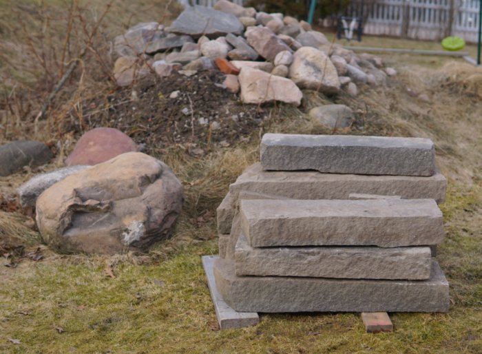 Stenblock arrangerade som trappsteg med en hög med stenar och byggmaterial i bakgrunden.