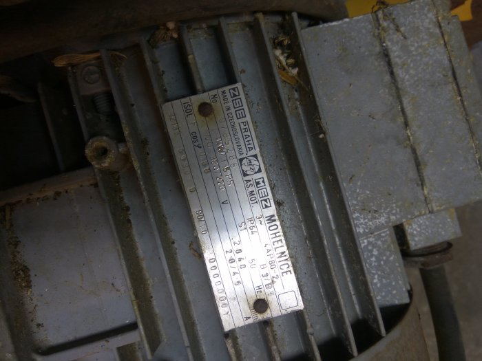Äldre industrifläkt med specifikationsetikett, smutsig i behov av eventuell reparation.