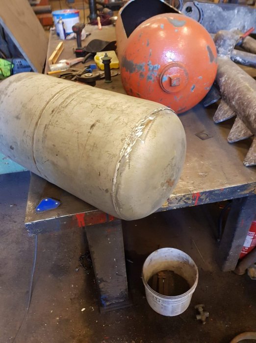 Bild på avsågad fot av en gasoltub i en verkstad med slipmärken för att förbättra utseendet.