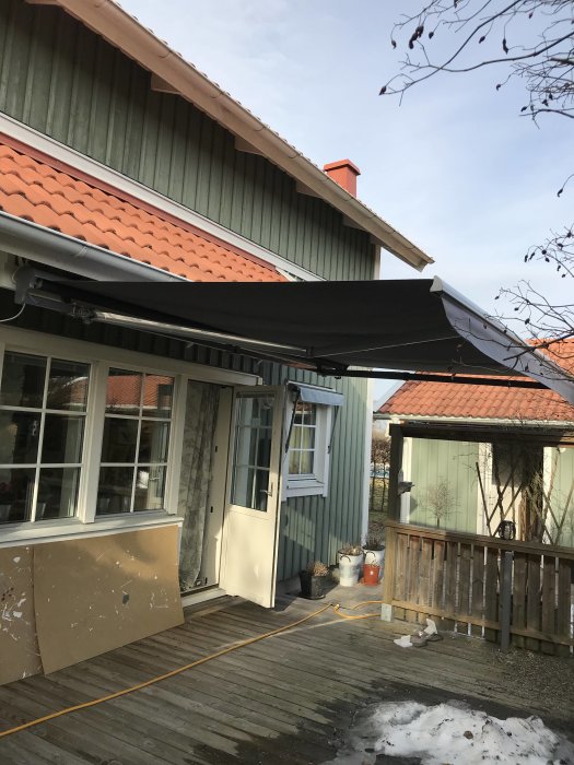 Nyinstallerad svart markis över husets terrass under en kristallklar kvällshimmel.