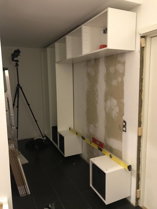Modifierade IKEA högskåpsstommar monterade på vägg under renovering med verktyg och material synligt.