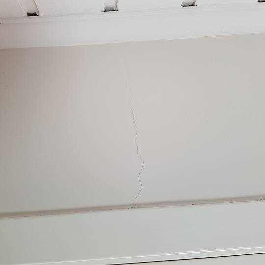 Sprikke i en hvit vegg under taket.