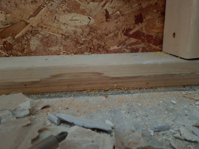 Vattenskada vid vägg med blött betonggolv, uppblött syll och rivet laminatgolv.