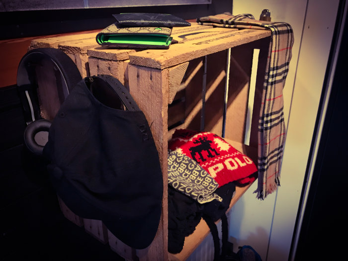 Vintage äppellåda använd som förvaring med hängande accessoarer och smartphone på toppen.