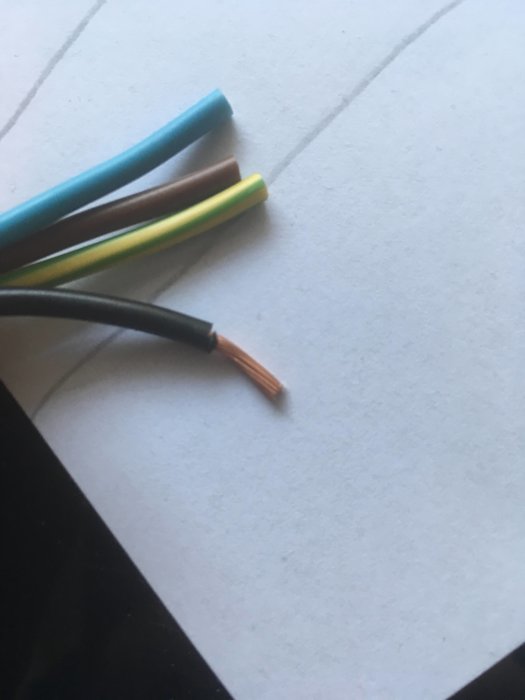 Elektriska kablar med avskalade ändar i färgerna blå, brun, gul/grön och svart på vit bakgrund.