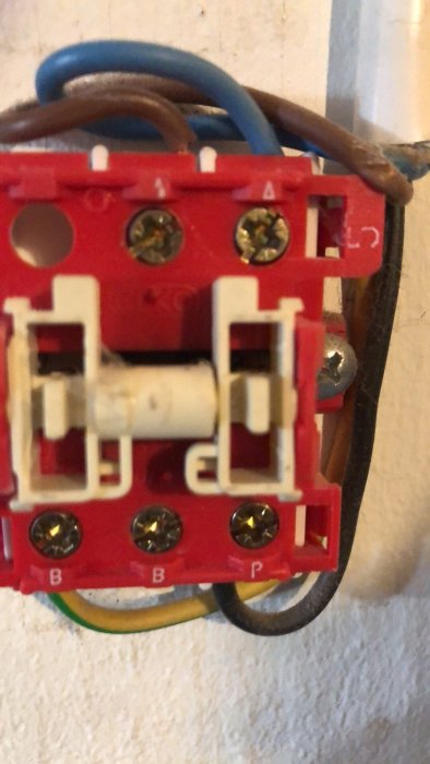 Närbild av en öppen elektrisk strömbrytare med synliga ledningar och anslutningsskruvar.