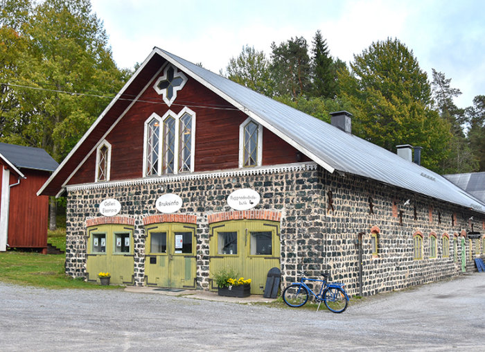 Olofsfors Bruk i Nordmaling med cykel framför och turkosa stenar på marken.