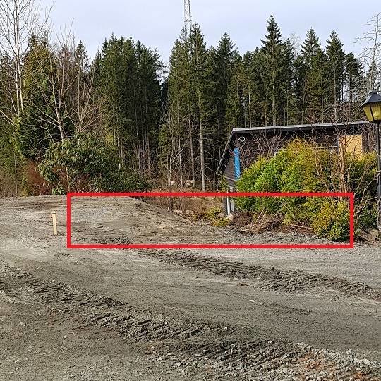 Uppgrävd del av tomt markerad med röd rektangel för planerad parkeringsplats.