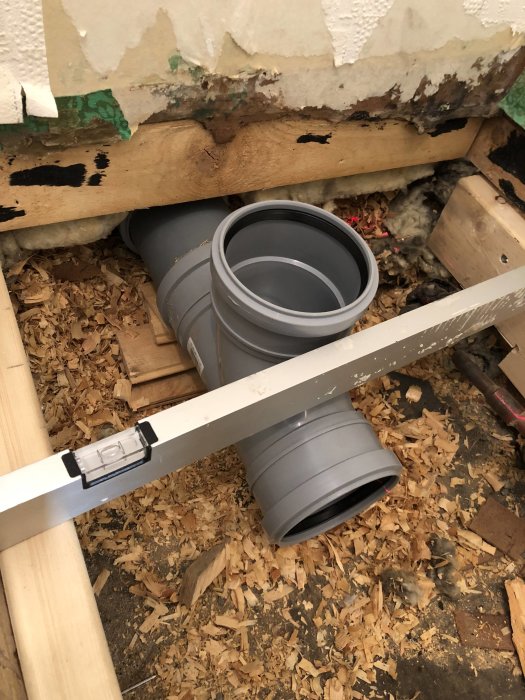 WC-stos och grenkoppling som sticker upp över golvnivån under en byggrenovering.