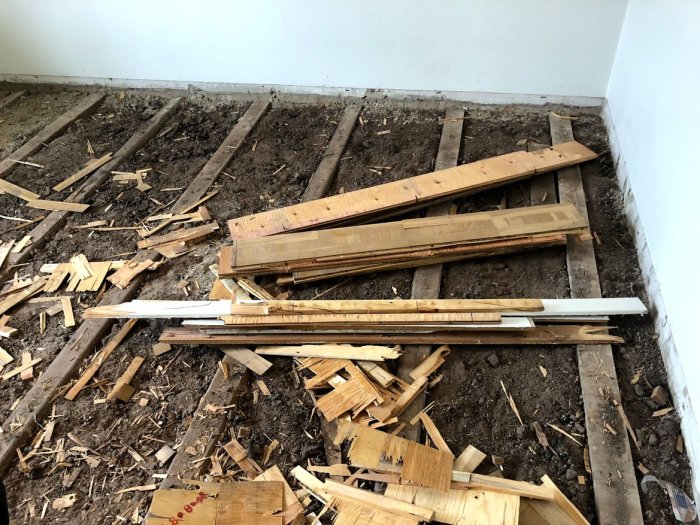 Golvrenovering med upprivna trägolv och synliga golvbjälkar samt spillvirke.