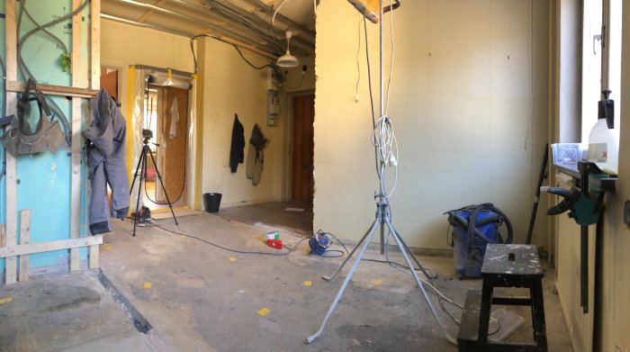 Ett pågående golvavjämningsprojekt i en tom lägenhet med betonggolv och verktyg utspridda.