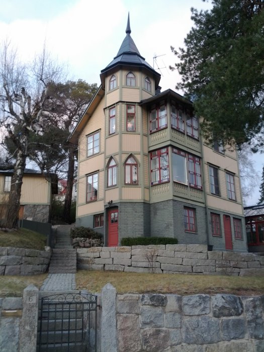 Gult hus i Duvbo, Sundbyberg, med ett lägre torn och traditionell arkitektur, omgivet av stenmur och grönska.