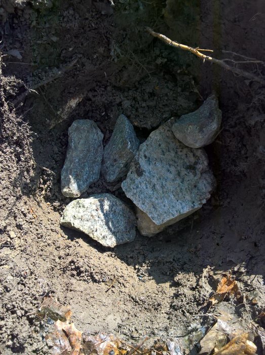 Stor grop med kalkstenar för dränering i trädgård, förberedelse för plantering av valnötsträd.
