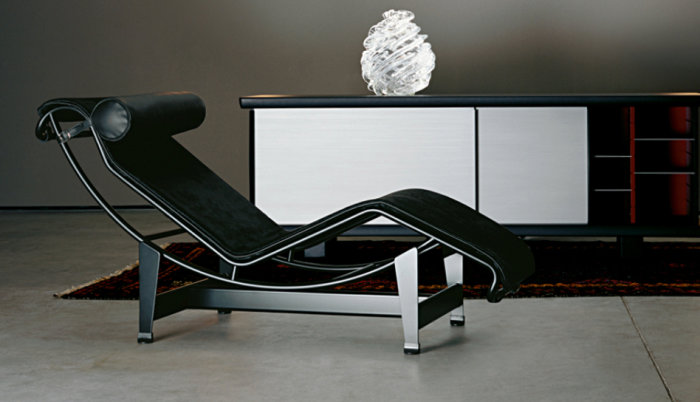 Svart Le Corbusier LC4 chaiselongue framför ett modernt vit och rött skåp på en orientalisk matta.