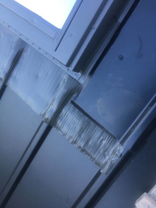 Detaljbild av ett nytt takfönster på plåttak med korrugerad skiva istället för plåt längst ner.