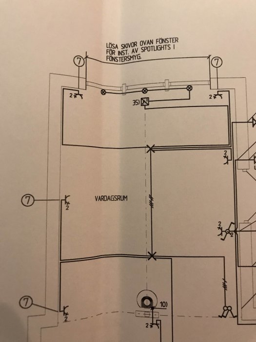 Planritning av ett vardagsrum som visar placeringen av takdosa, strömbrytare och förberedelse för spotlights.