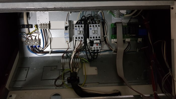 Öppet elskåp med elektriska komponenter som kretsbrytare och kablage, sannolikt en del av ett byggnadsprojekt.