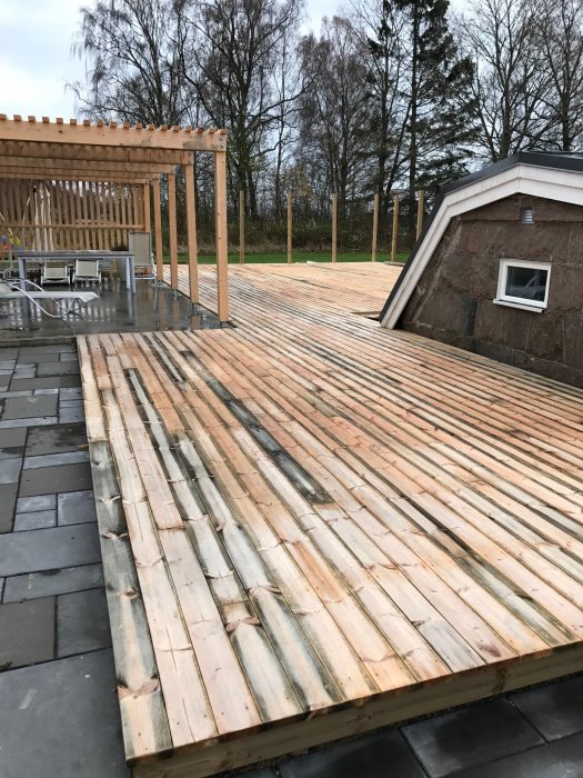 Nyinstallerad trall av kärnfuru med ojämn färgning, vissa brädor är mörkare med synliga svarta kanter.