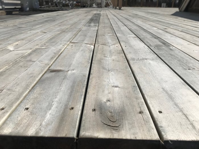 Gråsvarta missfärgningar på kärnfurutrall, synliga svarta kanter och ojämn färgton på verandan.