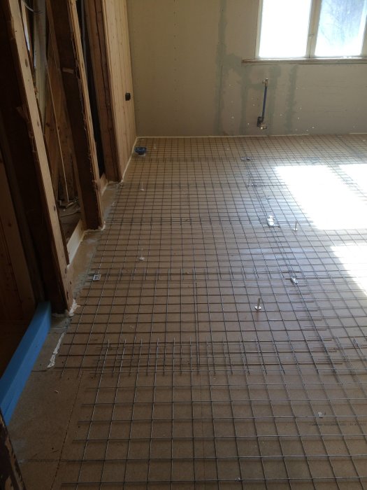Ett pågående arbete med flytspackling i ett badrumsutrymme, där golvets nät och förberedelser är synliga.
