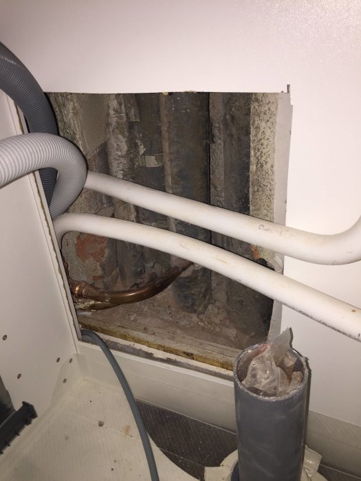 Rörinstallation bakom diskmaskin med skarvade rör som avviker från branschregler.