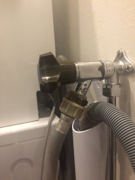 Vattenkran med anslutna slangar för en tvättmaskin, i behov av en extra anslutning för bänkdiskmaskin.