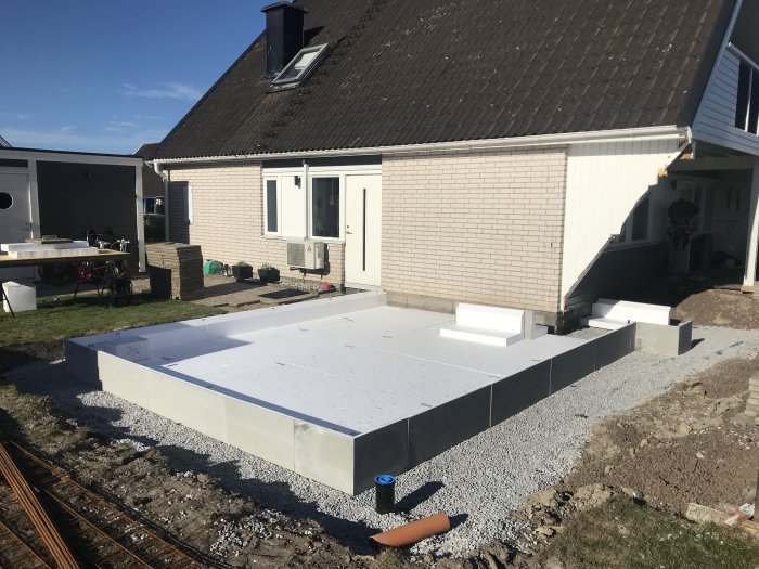 Ny utställd husgrund intill befintligt tegelhus ger en uppfattning om tillbyggnadens storlek.