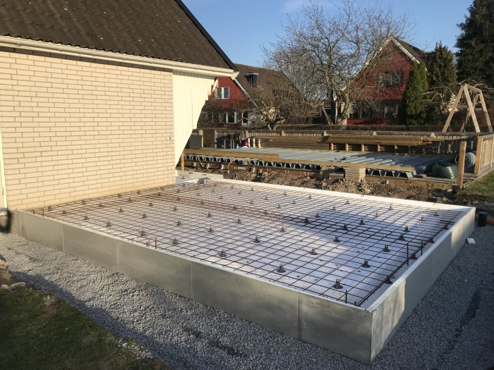 Grund för byggprojekt med armeringsjärn klar, men förskjutning nära balkongen synlig.