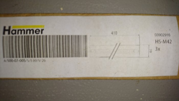 Etikett på en stålprodukt märkt "Hammer" med streckkod, artikelnummer och storlek HS-M42 visande ingen ytskada.