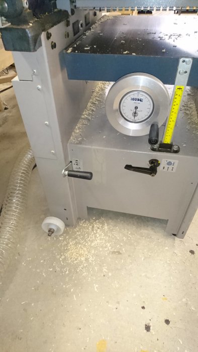 Hyvelmaskin med spån och sågspån runtomkring på golv och arbetsbord.