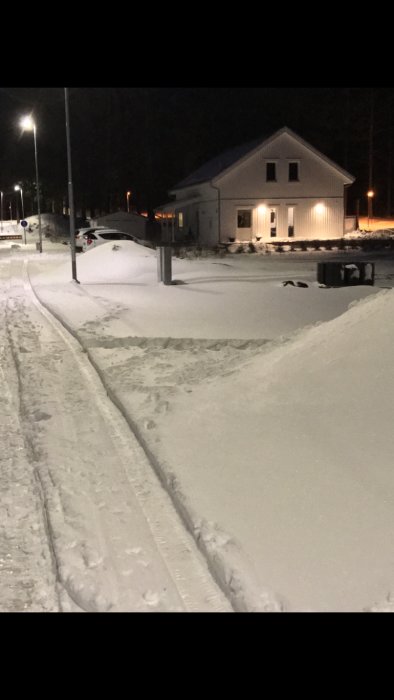 Elskåp och fiberskåp i snötäckt område vid tomtgräns, nattbild med lyktstolpar i bakgrunden.