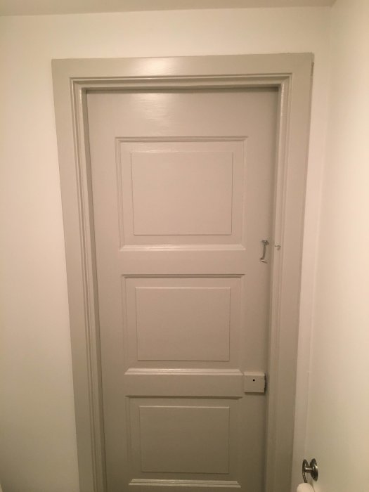 Stängd vit dörr i ett nymålat rum med vita väggar som del av en bostadsrenovering.