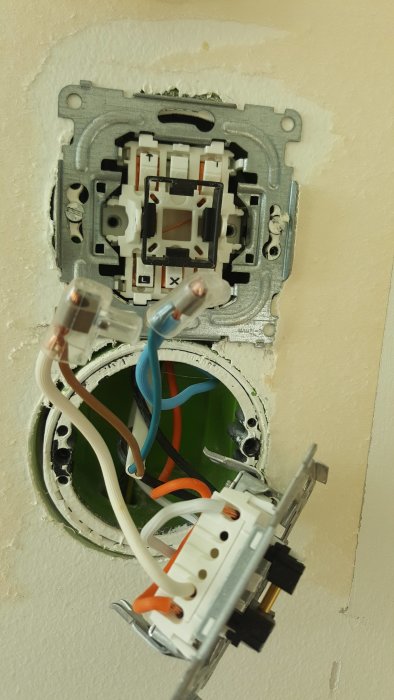 Öppen eluttag med elledningar som den tidigare ägaren kopplat för ledbelysning, med orange och blåa kablar framträdande.