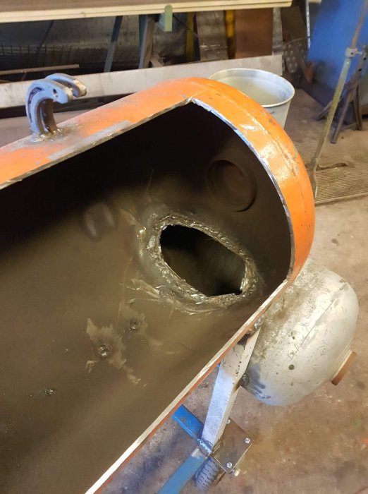 Metalltunna och vagn förenade med uppsågat hål mellan röklåda och matkammare i ett byggprojekt.