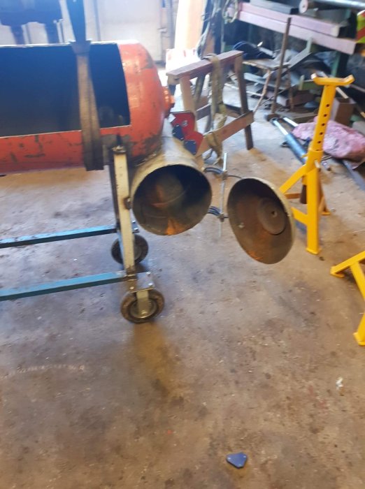En närbild av en hemgjord vedkap med ett rött cylindriskt hölje, placerad i en verkstad.