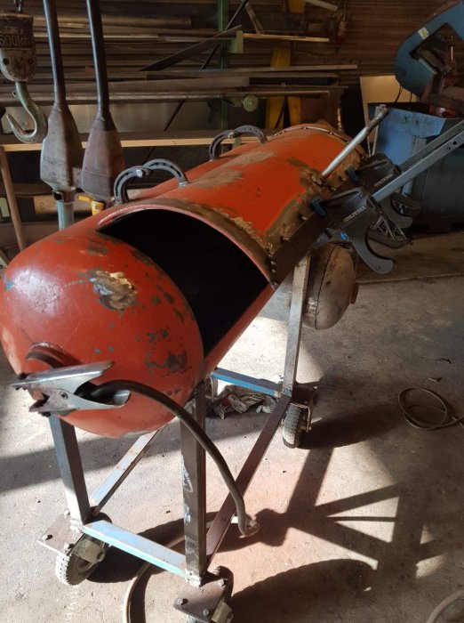 Begagnad bult svetsad som handtag på en öppen matlucka av en utomhusgrill under reparation.