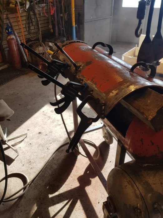 Metallkonstruktion med punktsvetsade sidoplåtar och provisoriskt svetsat handtag av en bult.